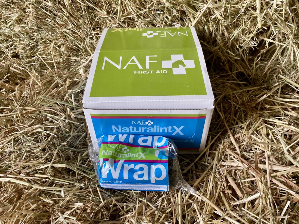 Product shot of a box of NAF First Aid Wraps with one wrap lying in front of the box