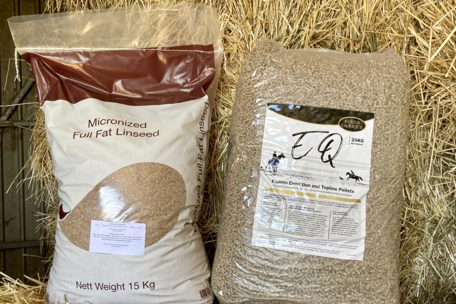 Product shot of one bag of EQ Micronized Full Fat Linseed and one bag of EQ Condition & Topline Cubes arranged together on a bale of hay