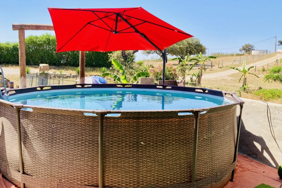 Standing outdoor swimming pool at Equus Ourique with red parasol on top of the pool giving shade