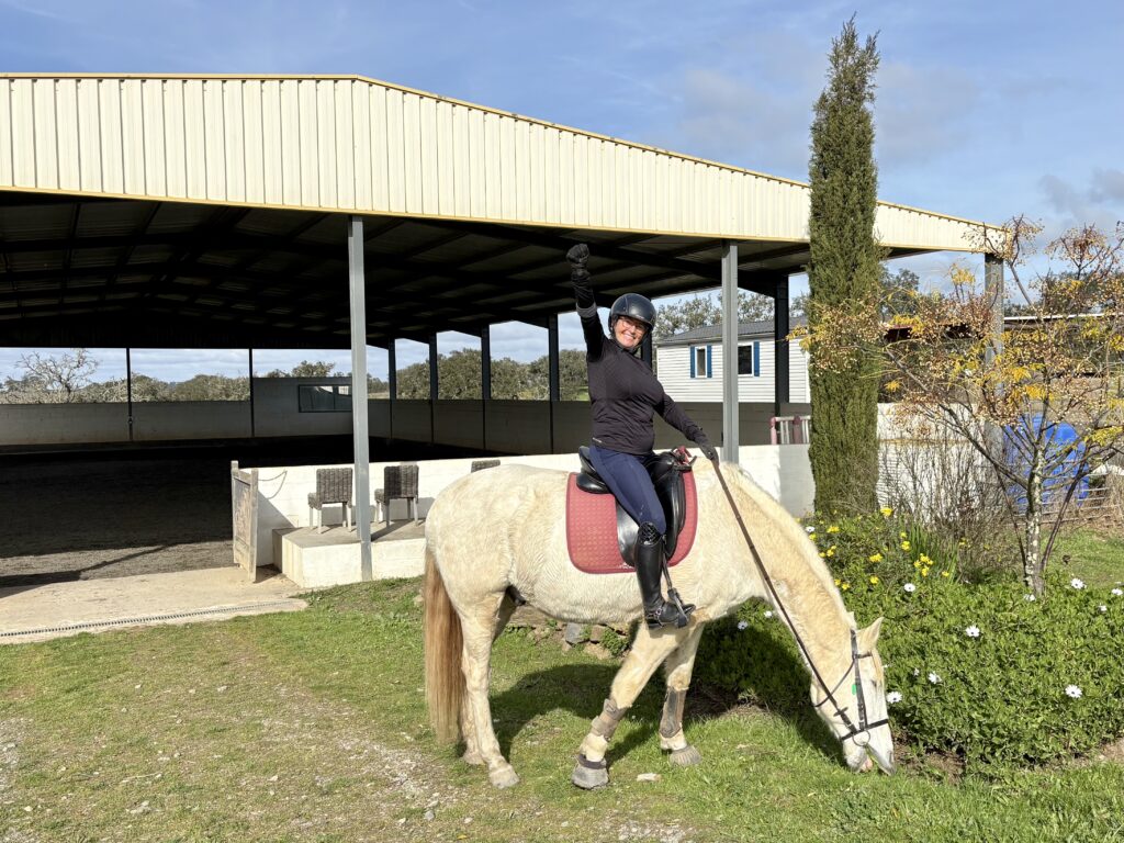 Woman on a white horse making a victory sign with her right arm